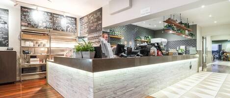 A modern restaurant with a brick counter, a ceiling fan, and a sign indicating an order point.