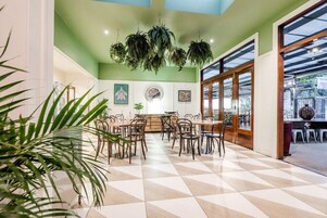 Un comedor amplio con piso a cuadros, plantas colgantes y vistas al exterior a través de amplias ventanas.