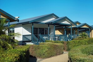 A row of beachside cabins with balconies, a covered walkway, and a clear blue sky. - West Beach Parks Resort (Adelaide)