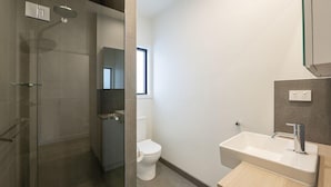 A modern bathroom with a glass shower enclosure, a toilet, and a sink with a mirror above it. - West Beach Parks Resort (Adelaide)