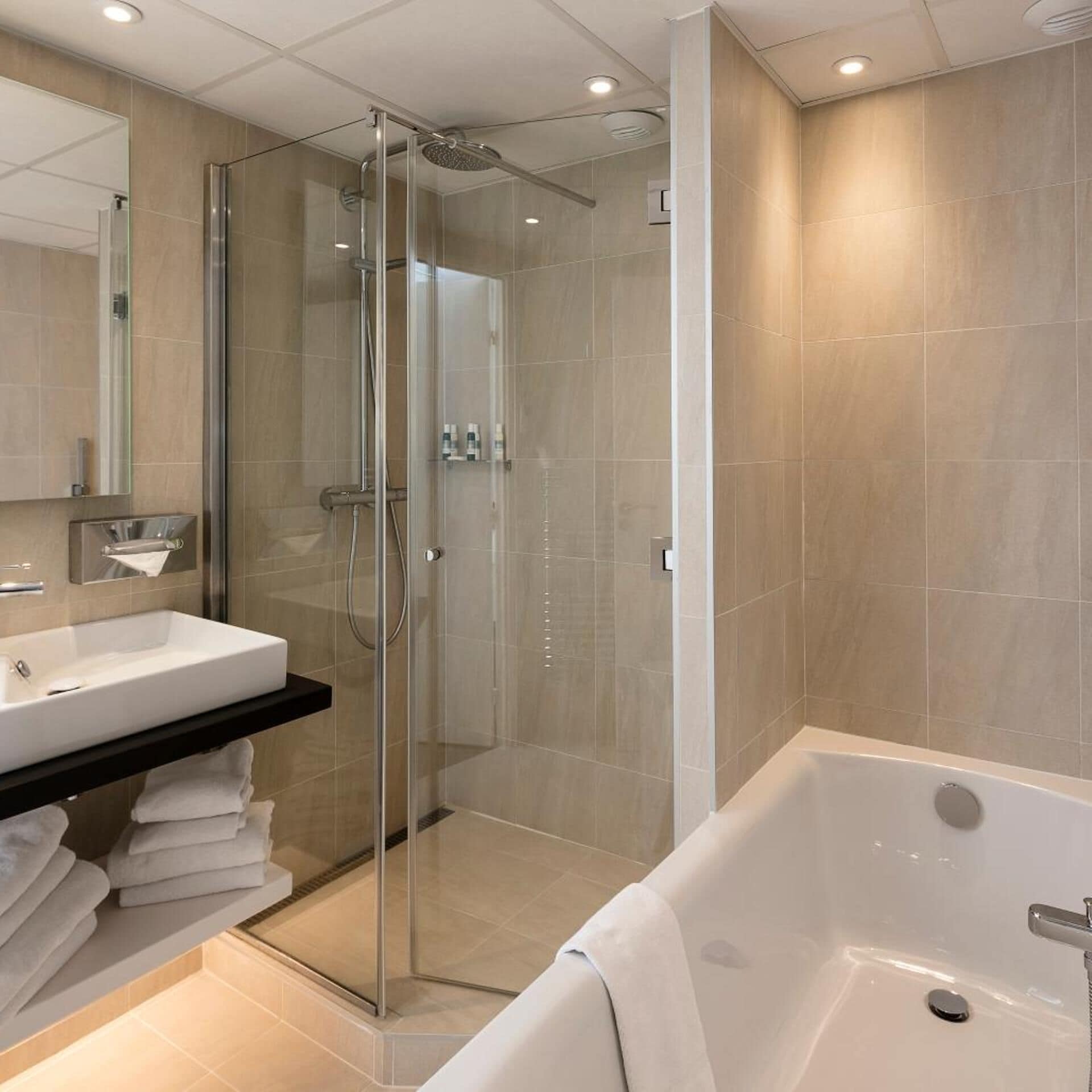 Un baño moderno con ducha envuelta en vidrio, una bañera blanca y un espejo grande.