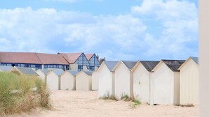 Une rangée de cabanes de plage, avec un bâtiment en arrière-plan.