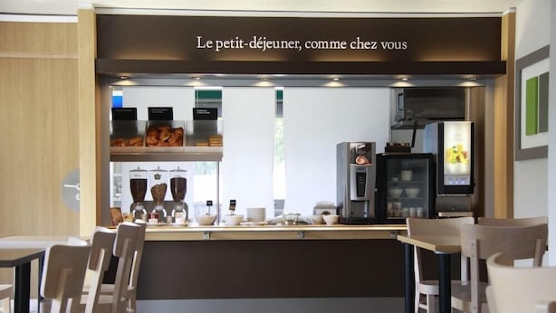 Een café met een balie, zitgedeelte en koffieapparatuur.