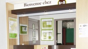 Een receptiebalie met een bordje met daarop 'Bienvenue chez B&B' en een klein display met brochures.