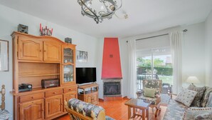 A living room with a television, wooden furniture, a fireplace, and a view of the outdoors. - Casa Rural El Robledal with Private Pool near Segovia & Madrid, Sleeps 8 (Zarzuela del Monte)