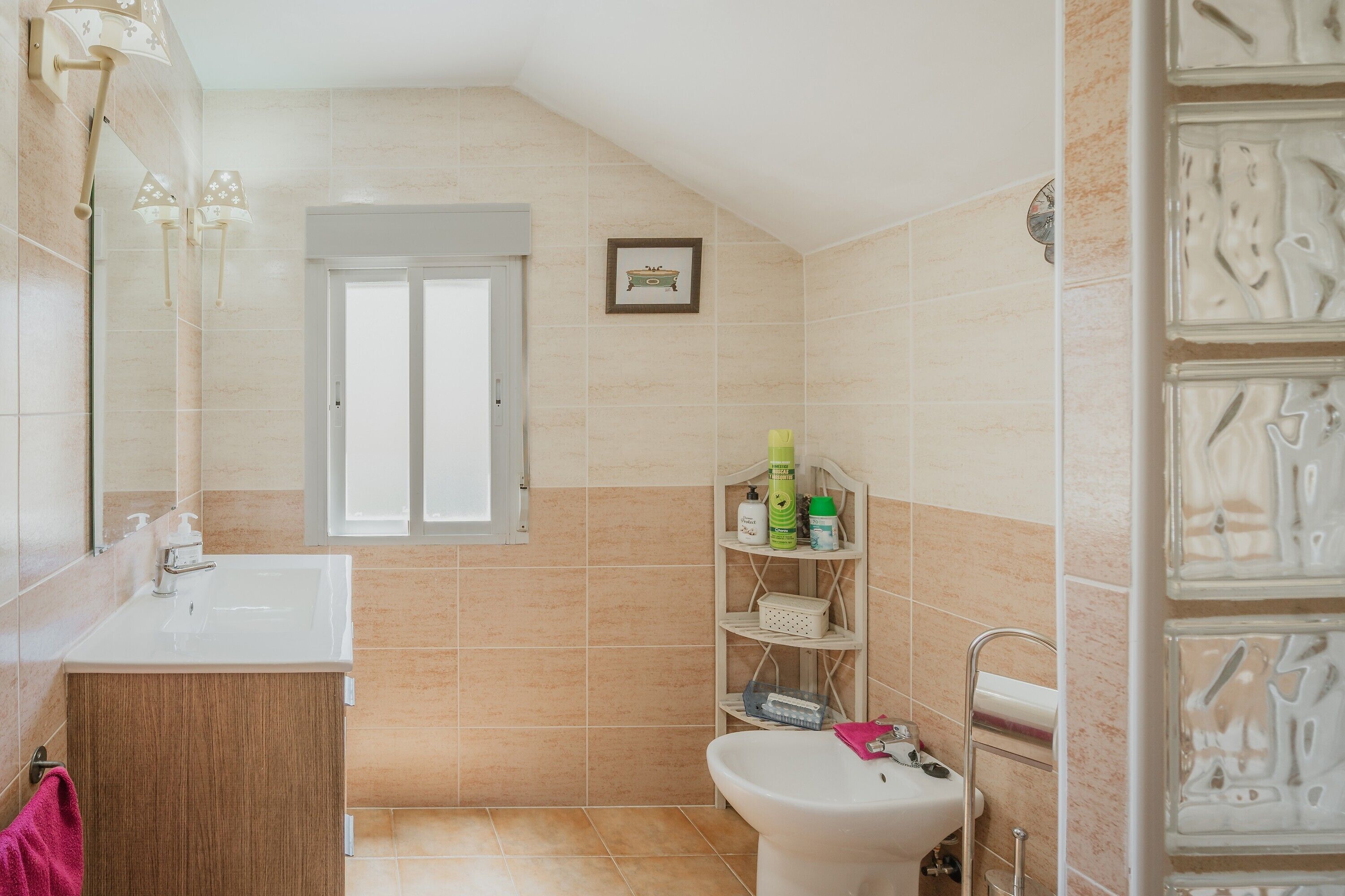 A bathroom with a sink, toilet, and shelves with toiletries.