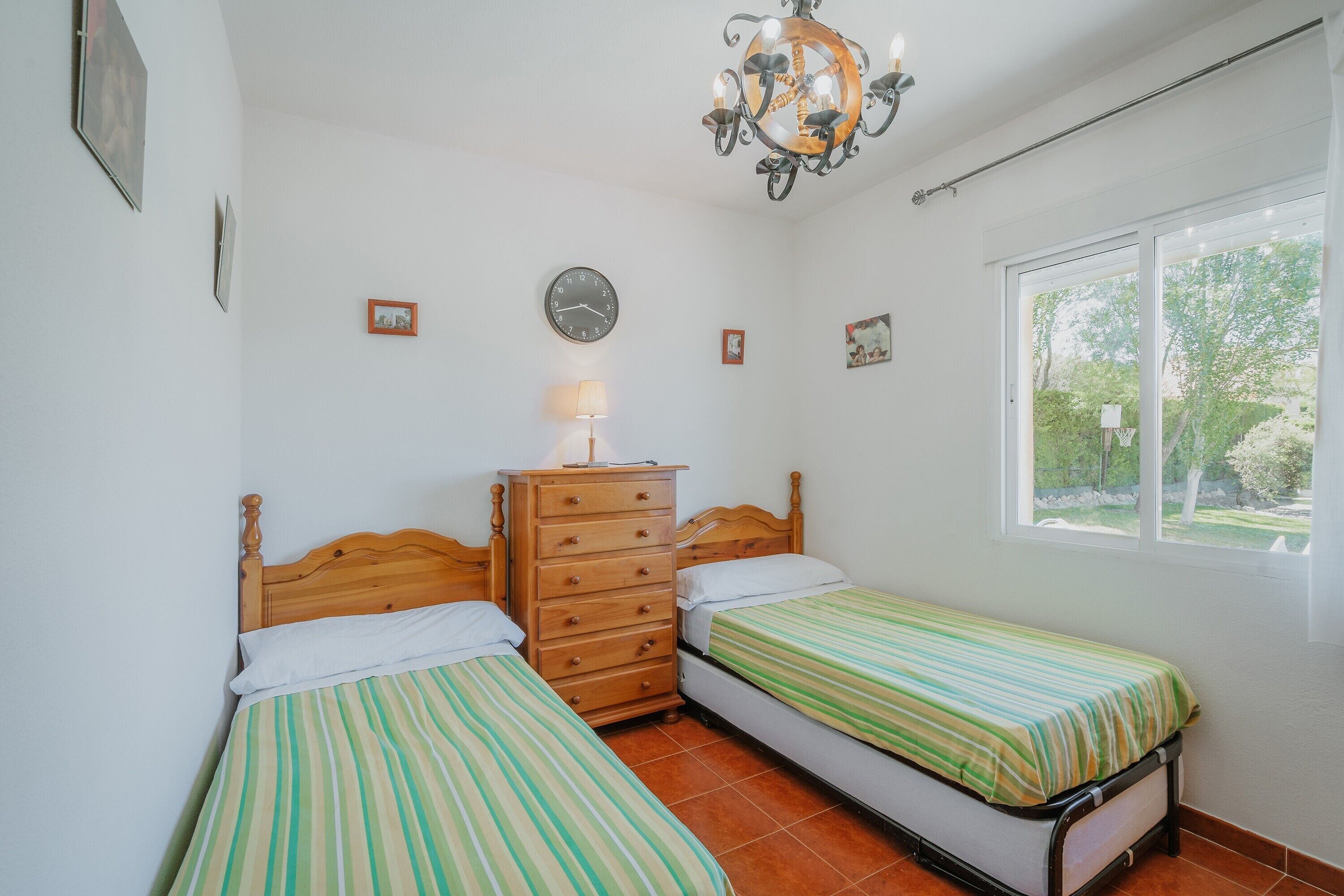 Ein Schlafzimmer mit zwei Betten, einem Schminktisch, einer Kristallleuchtre, einer Uhr und einem Fenster mit Blick.