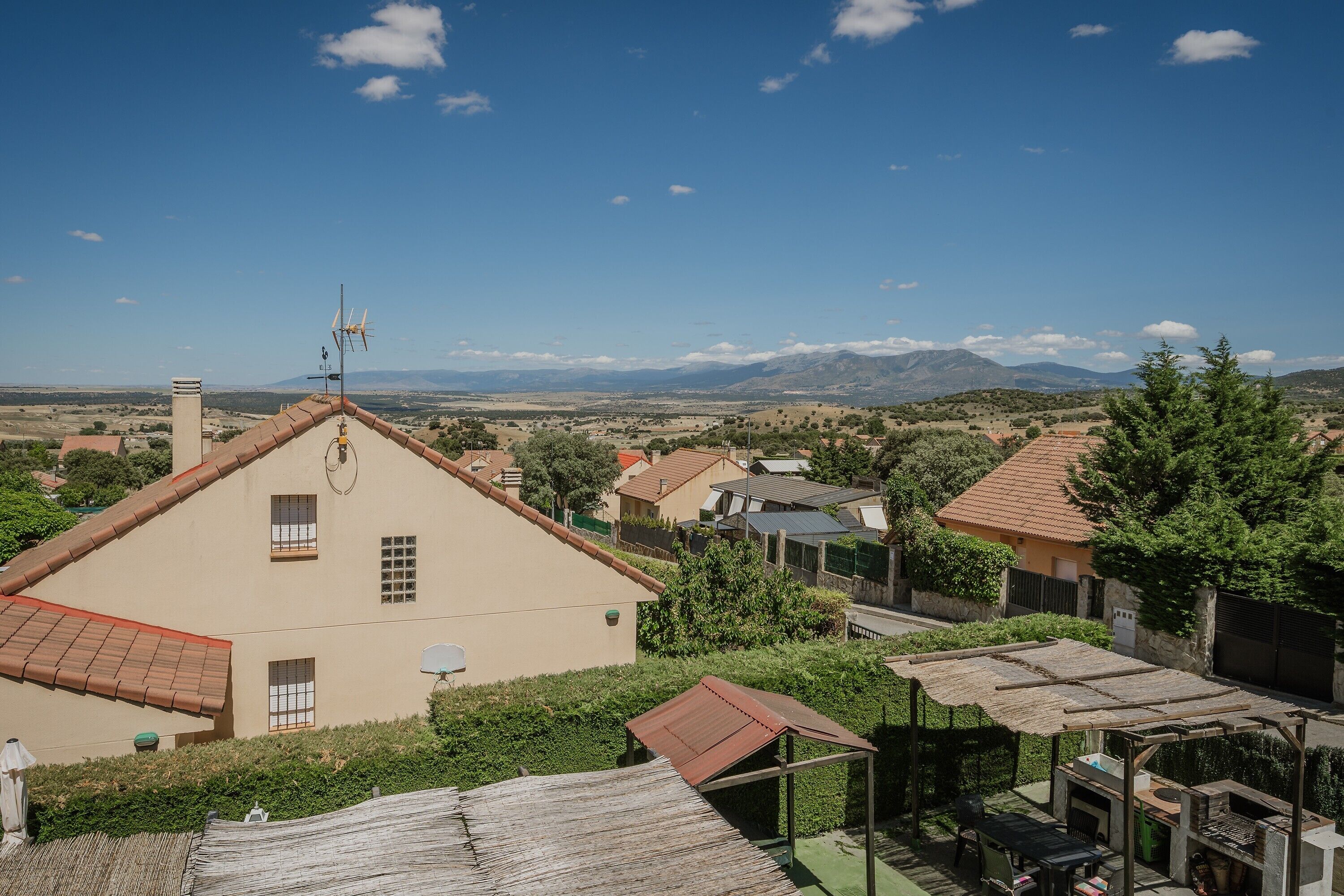 Un barrio residencial con casas, cielo despejado y montañas a lo lejos.