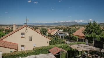 Un barrio residencial con casas, cielo despejado y montañas a lo lejos.