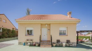A two-story house with a tiled roof, a front door, and a small porch with chairs. - Casa Rural El Robledal with Private Pool near Segovia & Madrid, Sleeps 8 (Zarzuela del Monte)