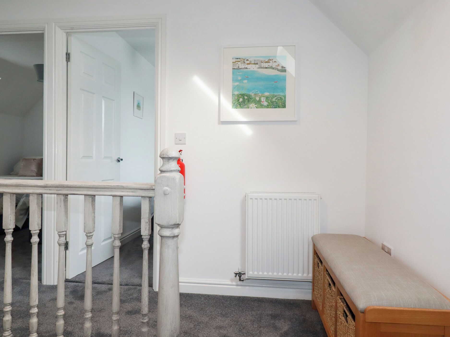 A hallway with a white door, a radiator, a bench, and a framed picture on the wall.
