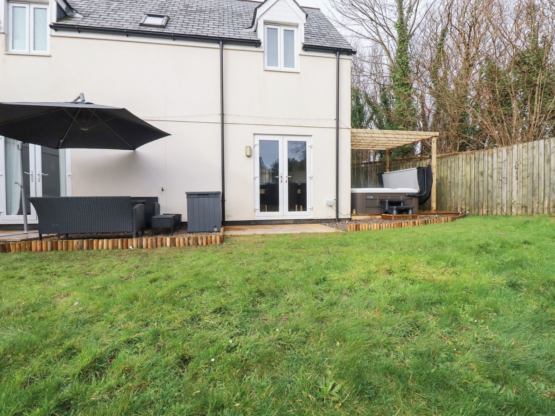 A two-story house with a patio area, a sliding glass door, and a wooden deck.