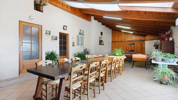 A dining area with wooden tables and chairs, a large window, and a ceiling fan.