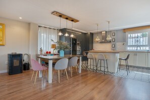 A modern kitchen with a dining area, wooden flooring, and pendant lighting.