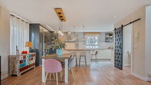 Een moderne keuken met een houten eettafel, stoelen en hanglampen.