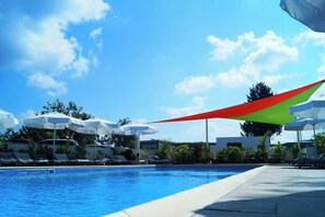 Ein Schwimmbecken mit Liegestühlen und Sonnenschirmen.