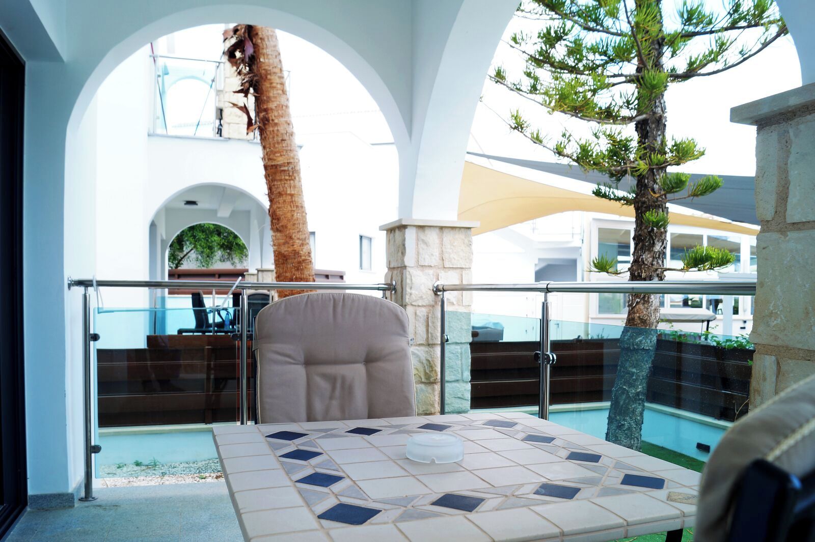 Un área de estar al aire libre con luz solar, una mesa, sillas y una palmera.