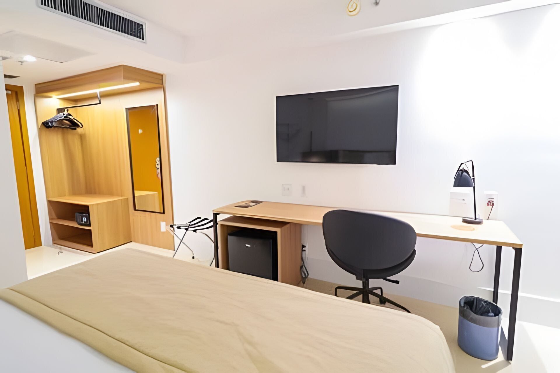 Een slaapkamer met een bed, een bureau, een stoel, een televisie en een kledingkast.