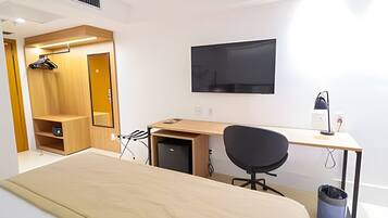 Een slaapkamer met een bed, een bureau, een stoel, een televisie en een kledingkast.