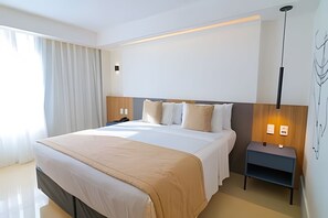 A modern hotel room with a large bed, bedside tables, a nightstand, and a wall-mounted light fixture. - Ozped Flats Particulares  Condomínio das Nações I Acesso pelo Hotel Tryp  (Brasília)