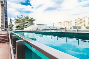 Une piscine offrant une vue dégagée sur les bâtiments et les arbres environnants.