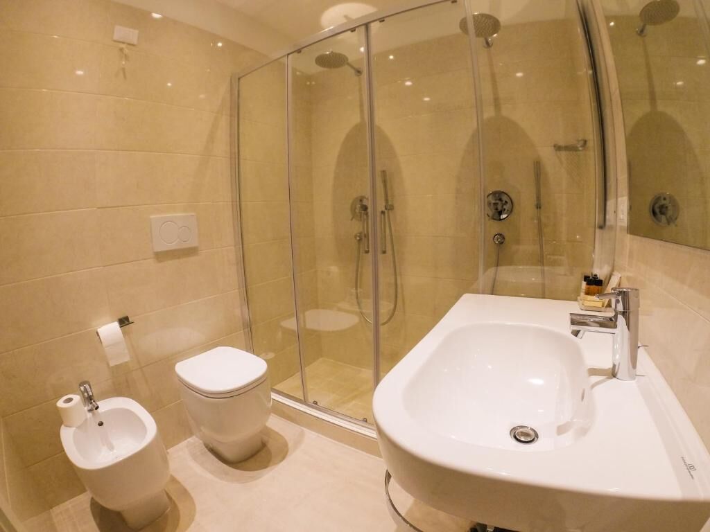 A modern bathroom with a glass-enclosed shower, a standalone toilet, and a large sink with a mirror.
