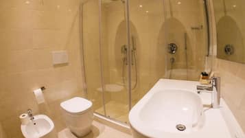 A modern bathroom with a glass-enclosed shower, a standalone toilet, and a large sink with a mirror.