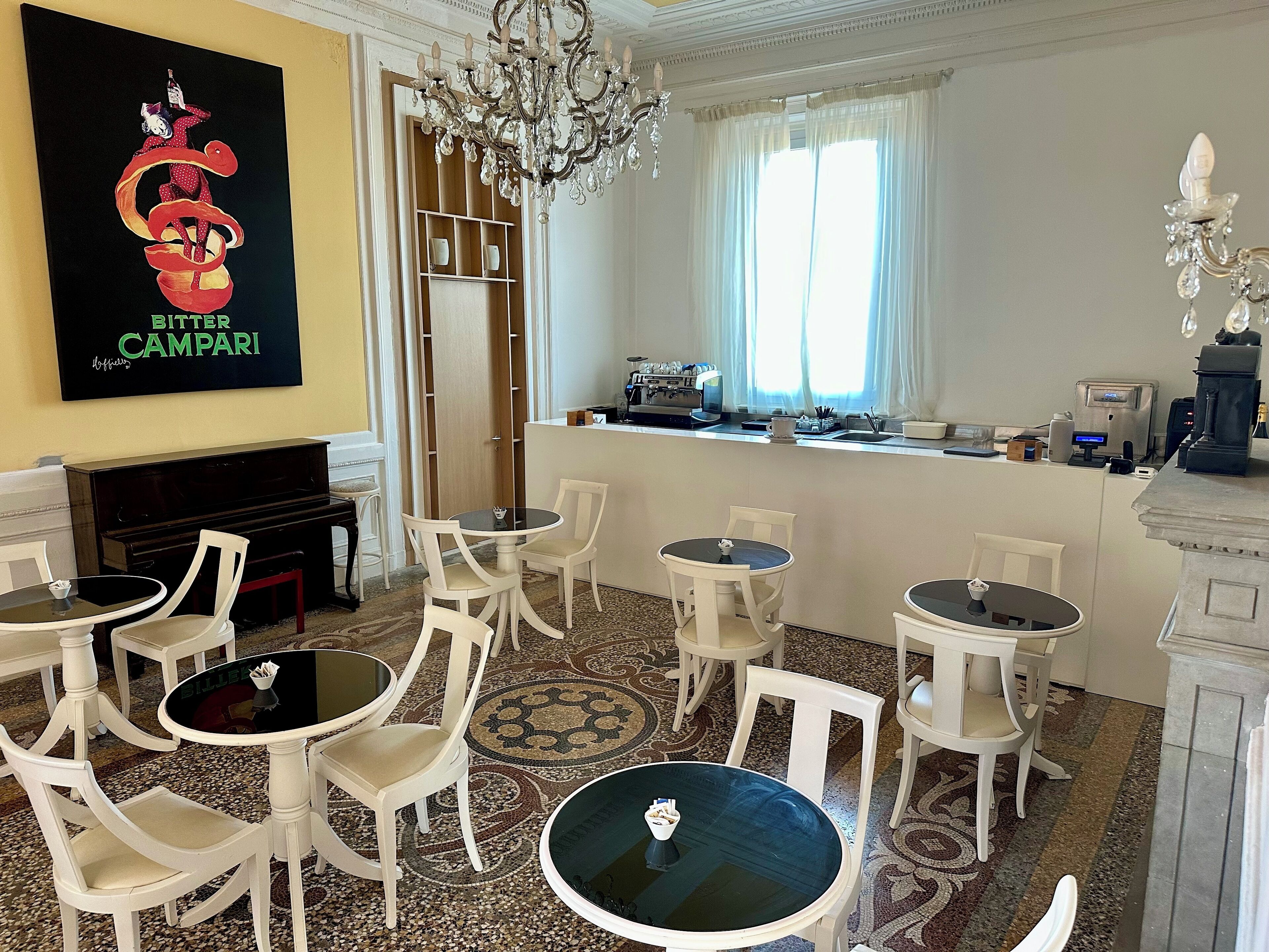 Habitación de hotel con comedor, bar, piano y un cartel grande en la pared.
