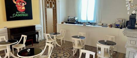 Habitación de hotel con comedor, bar, piano y un cartel grande en la pared.