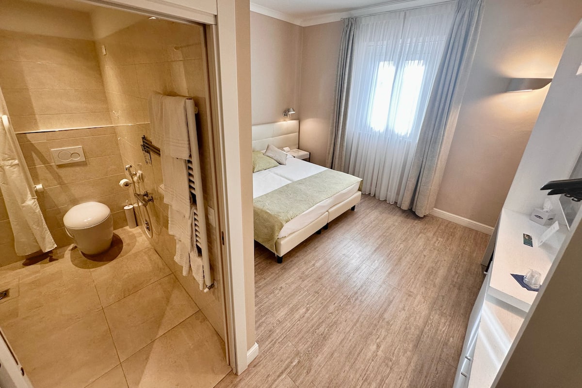 Un dormitorio moderno con una cama grande, un baño separado con ducha y un vestidor.