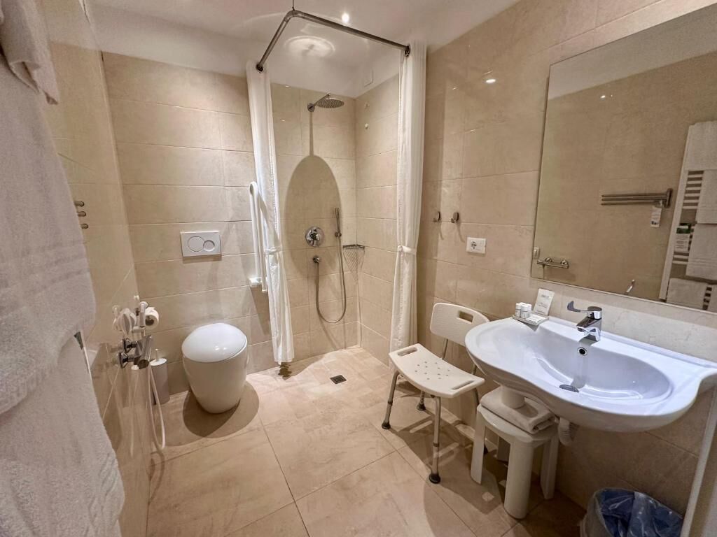 Ein modernes Badezimmer mit Dusche, Toilette, Waschbecken und einem Sessel.