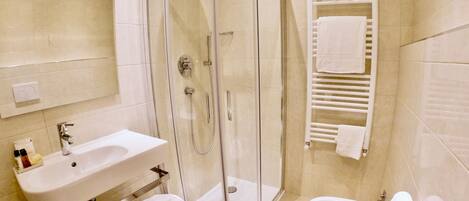 A modern bathroom with a glass-enclosed shower, a sink with a mirror, and a toilet.