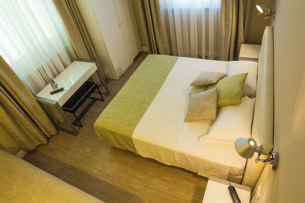 Una habitación de hotel con cama, mesita de noche y escritorio con silla.