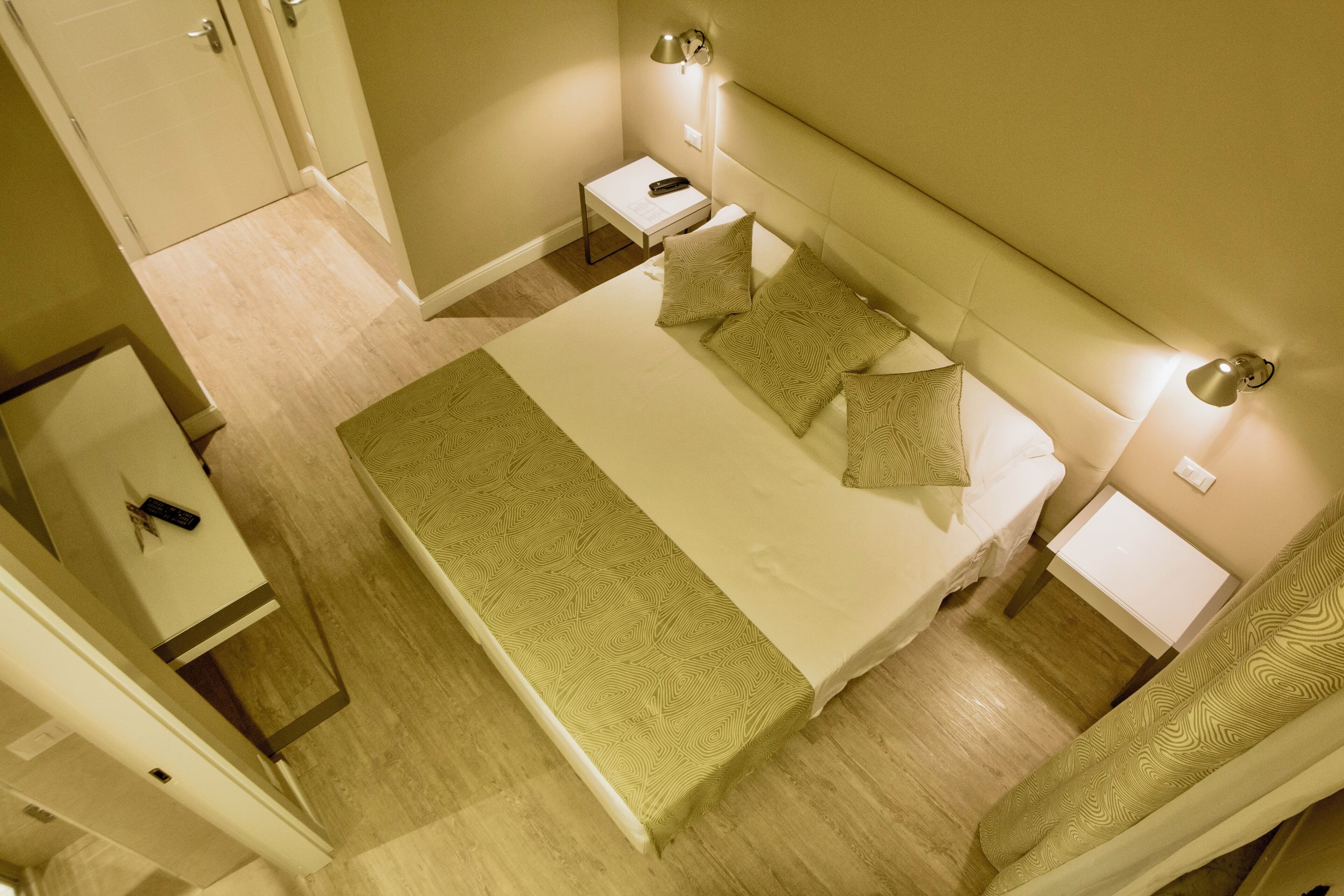 Une chambre d’hôtel avec un grand lit, deux tables de chevet, une petite table et une armoire.