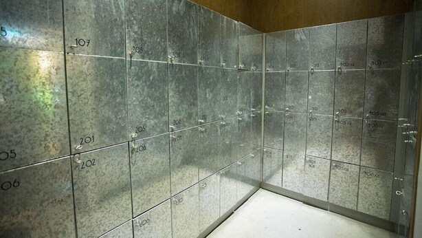 Ein Badezimmer mit gefliesten Wänden und Boden, nummerierten Schließfächern und einer Holzzieldecke.