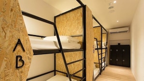 Ein Schlafraum mit Etagenbett, Holzwand und Kleiderschrank.