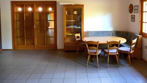 Ein Essbereich mit einem runden Tisch, Stühlen, Holzschränken und einer Deckenleuchte.