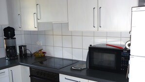 Eine moderne Küche mit weißen Schränken, einer schwarzen Arbeitsplatte, einer Kaffeemaschine, einer Mikrowelle und einem Backofen.