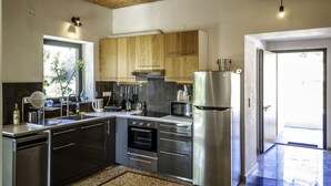 A modern kitchen with stainless steel appliances, wooden cabinets, and a large window. - Myrtia Beach House (Chania)