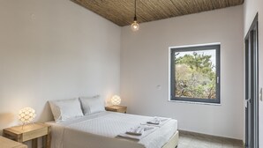 A bedroom with a bed, bedside tables, a window with a view of trees, and a ceiling with a woven pattern. - Myrtia Beach House (Chania)