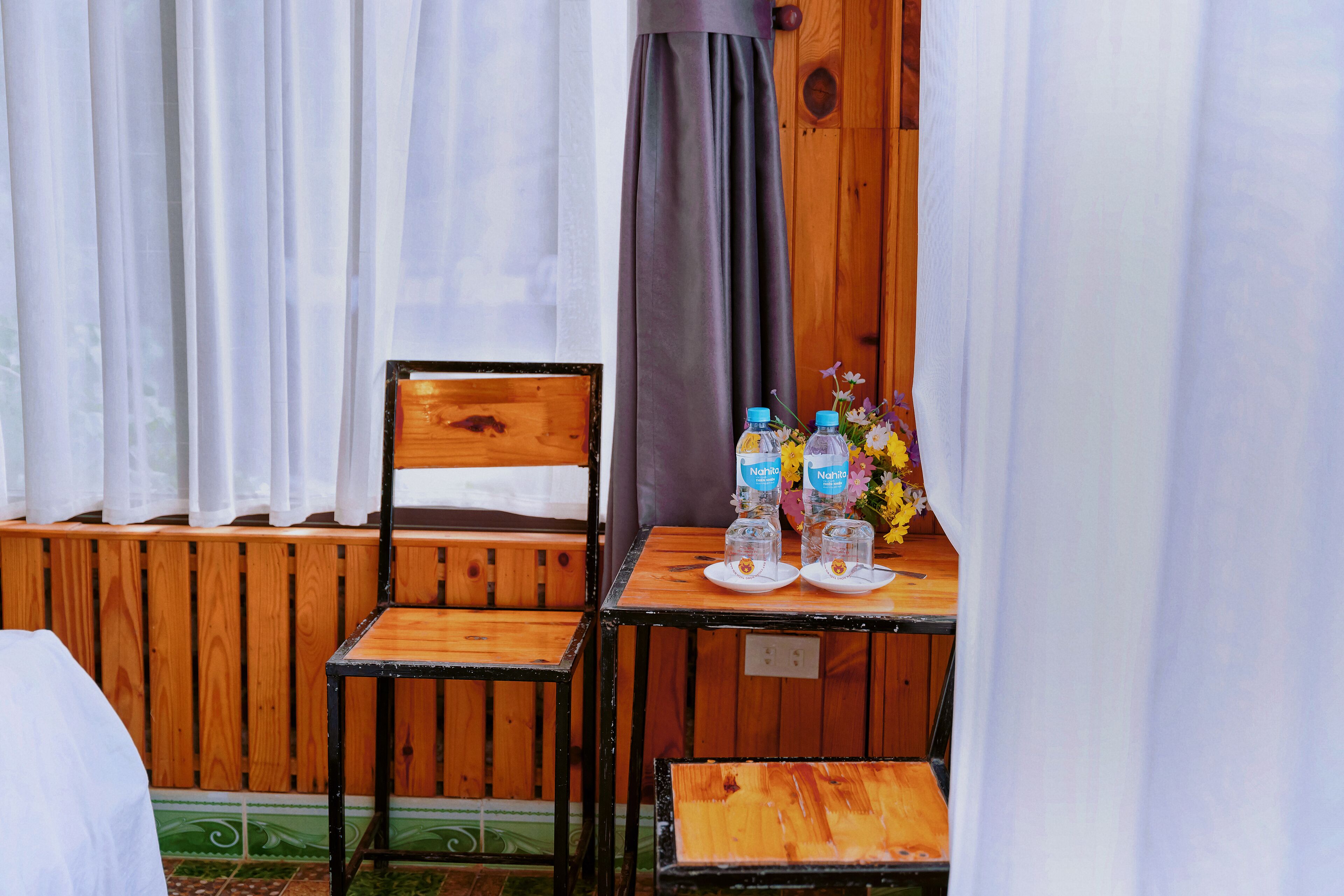 Una silla y una mesa de madera, con botellas de agua y un florero.