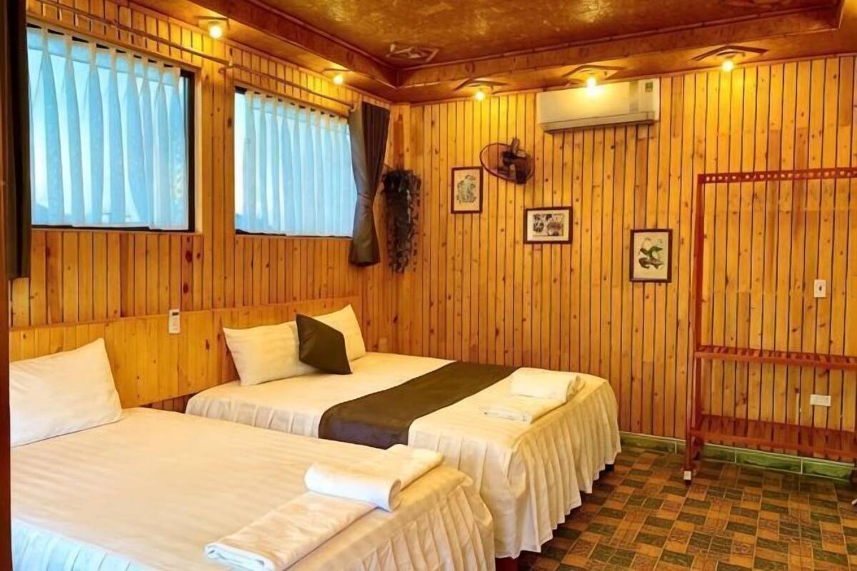 Quarto com duas camas, paredes de madeira e chão xadrez.