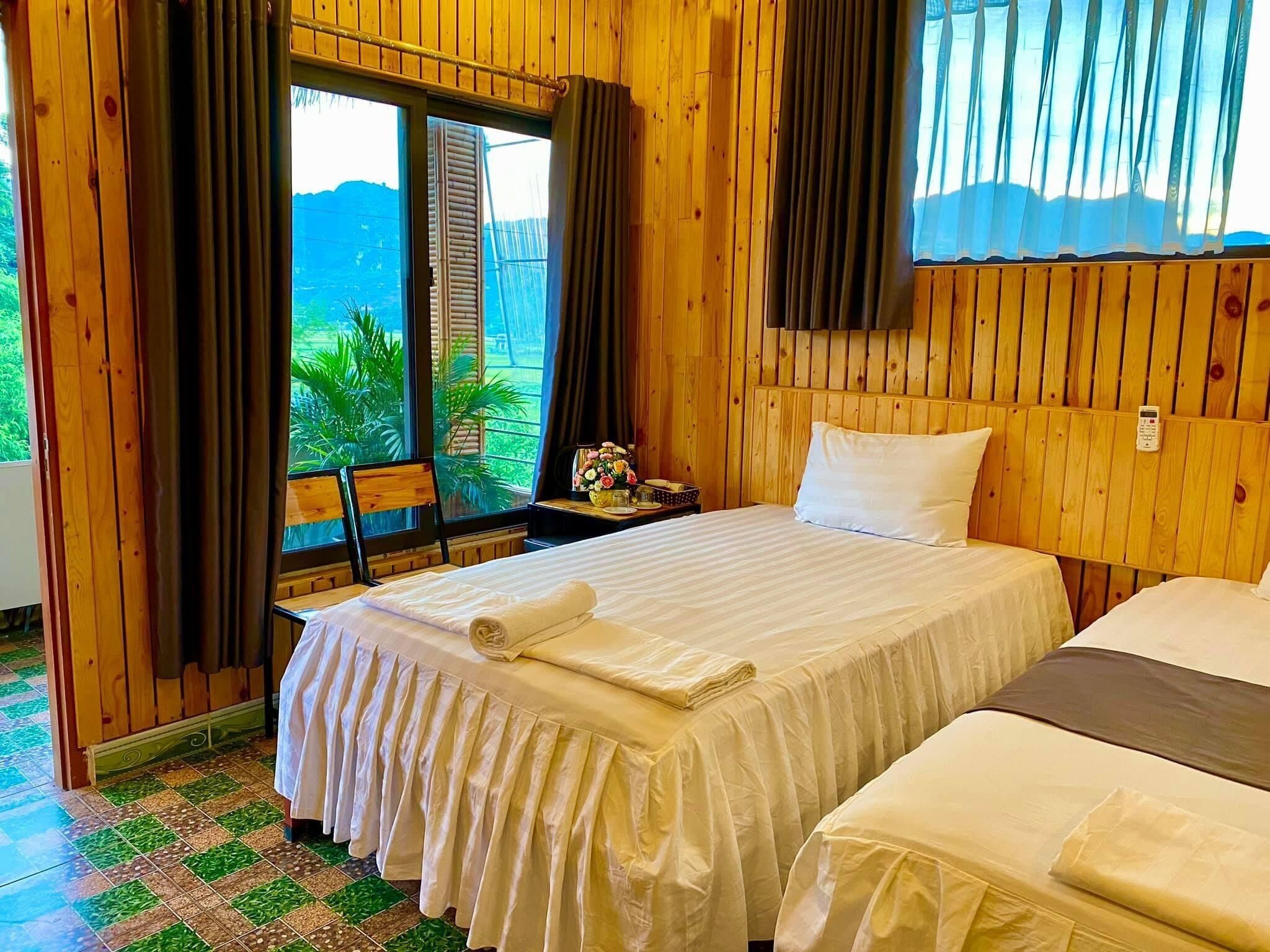 Una habitación con una cama grande, otra más pequeña, una mesita de noche con un teléfono y una ventana con cortinas.