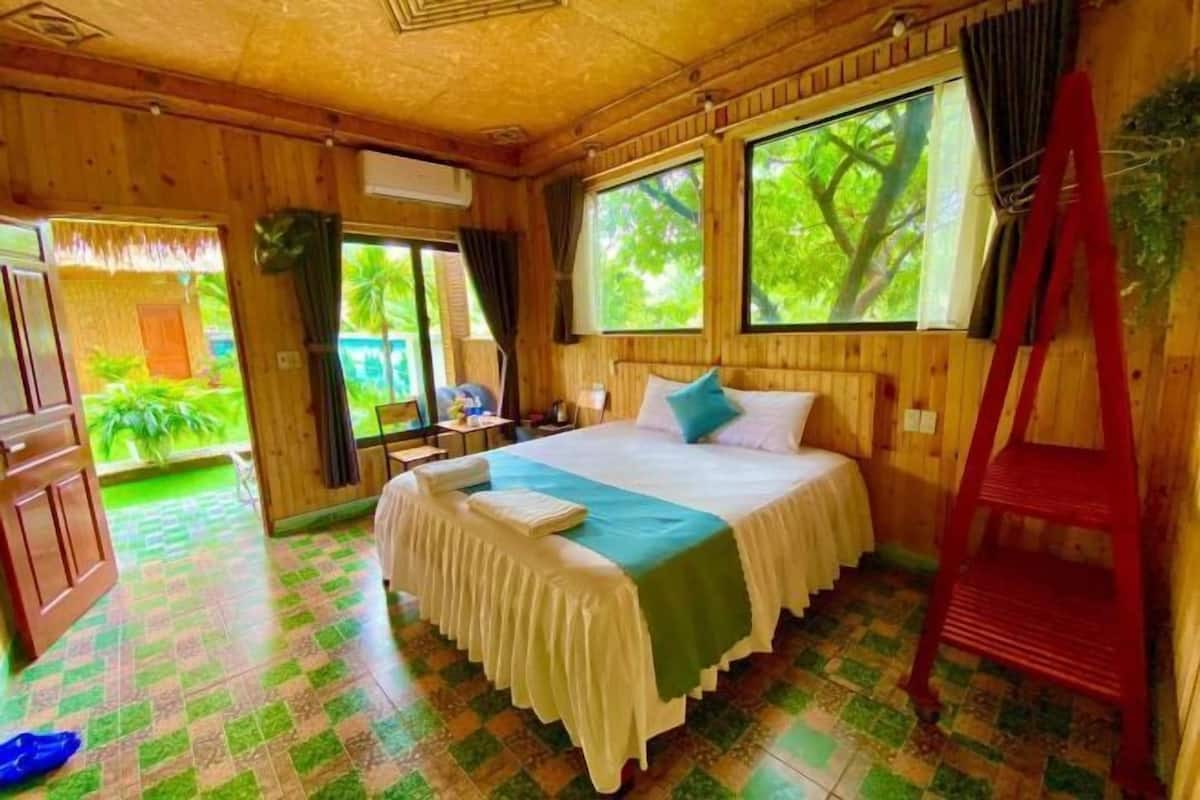 Um quarto de madeira com uma cama, uma janela, uma porta e uma escada vermelha.