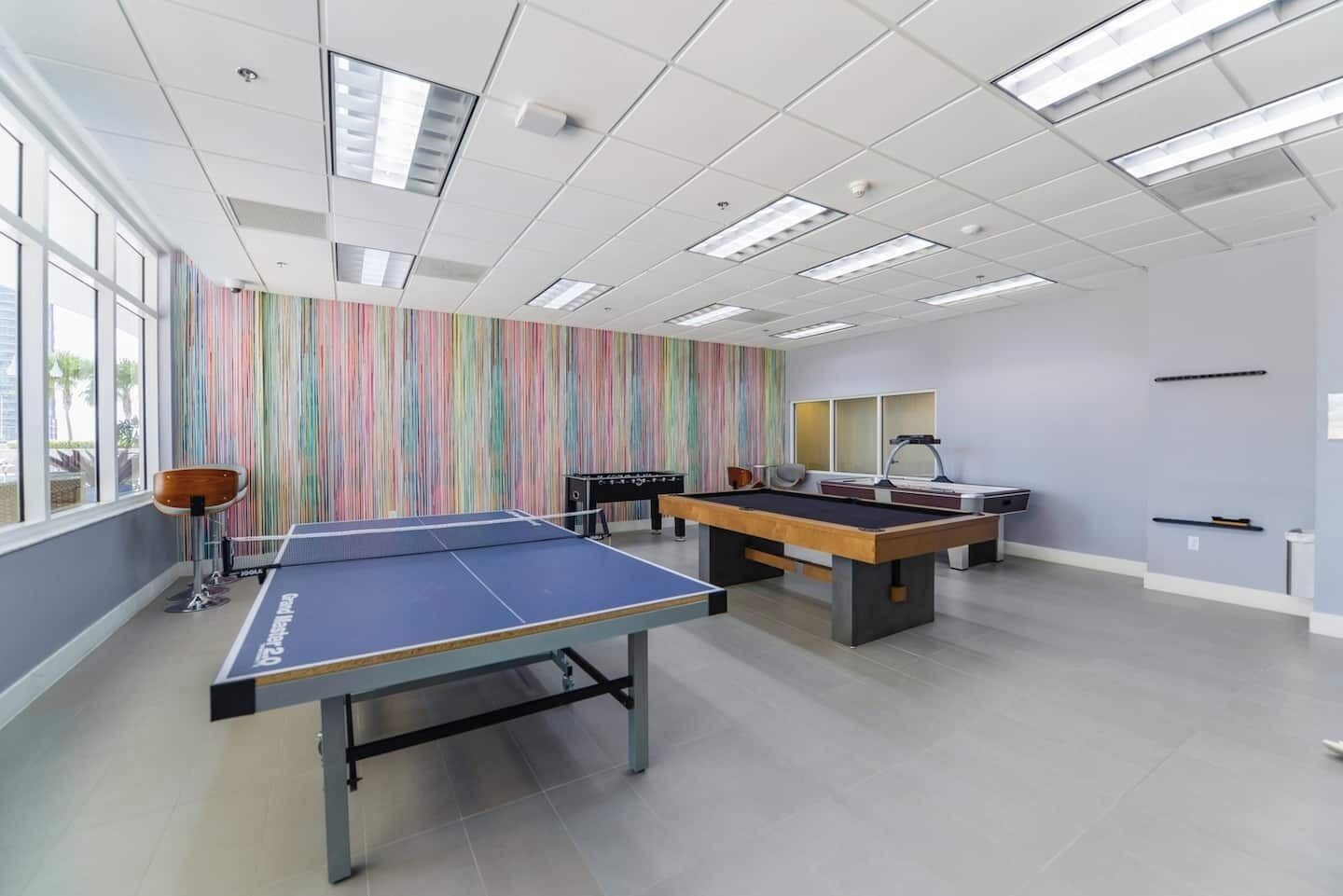 Une pièce équipée d’une table de ping-pong, d’un baby-foot et d’un tapis de course.