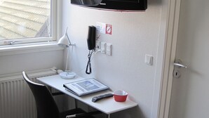 A small, compact room with a desk, chair, and a mounted television. - Fredrikshavn Hotel First Partner (Frederikshavn)