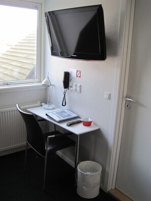 A small, compact room with a desk, chair, and a mounted television. - Fredrikshavn Hotel First Partner (Frederikshavn)