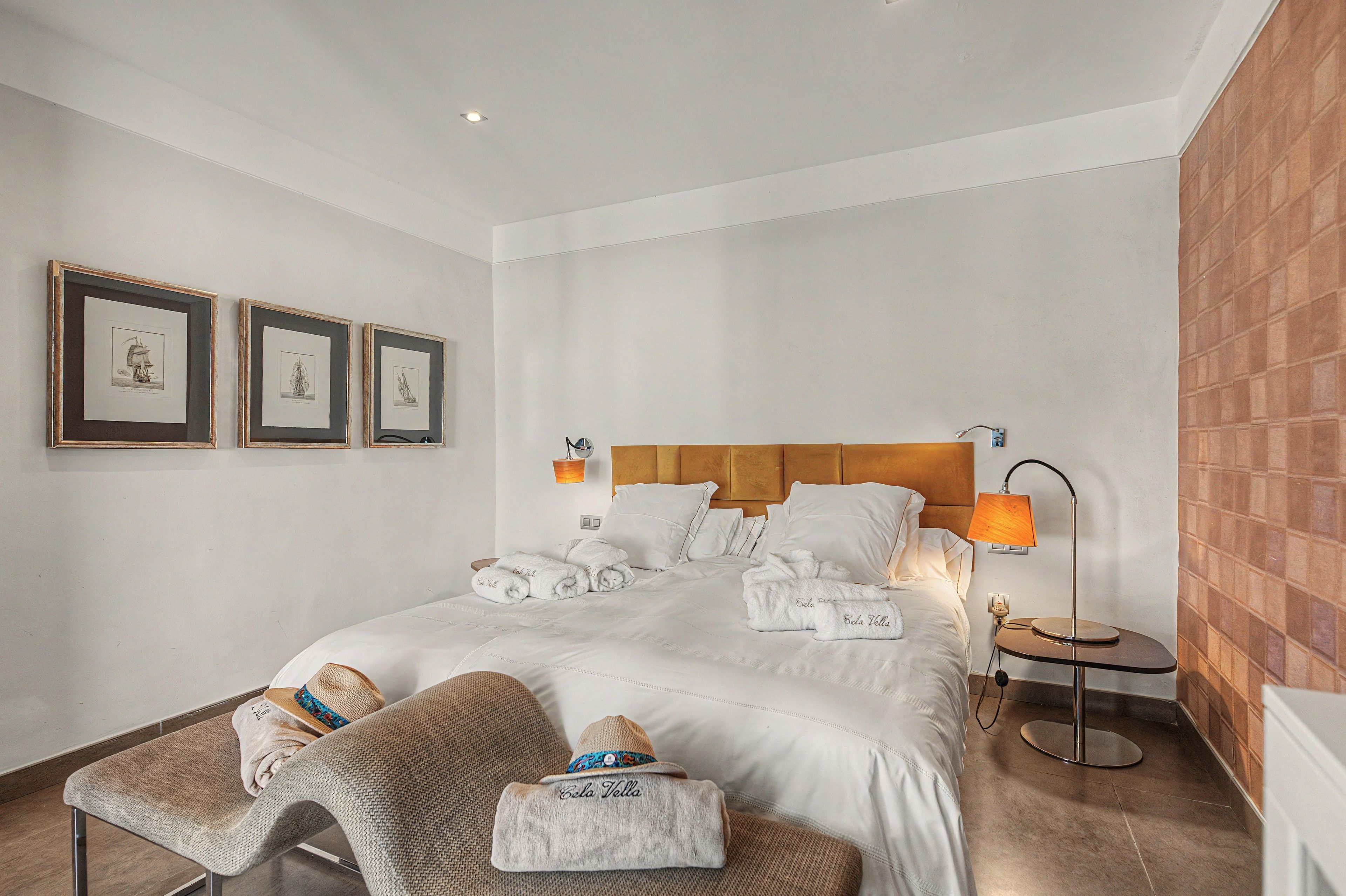 Une chambre d’hôtel avec un lit, deux tableaux encadrés au mur, une lampe de chevet et une petite table avec une lampe.