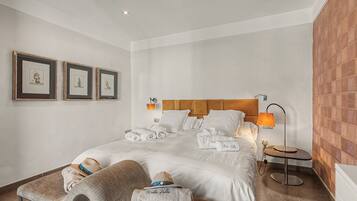 Una habitación de hotel con una cama, dos cuadros en la pared, una lámpara de noche y una mesita con una lámpara.