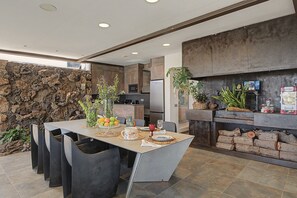 Una cocina moderna con pared de piedra, una mesa de comedor con sillas y una estufa empotrada.